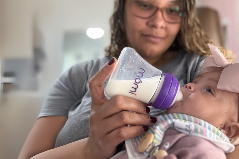 mama offers mōmi bottle to her baby